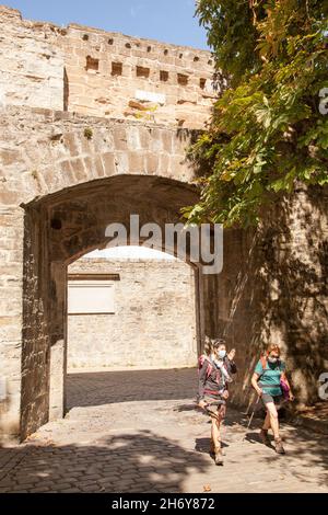 Pellegrini che camminano attraverso le porte della città a Camino de Santiago la via del pellegrinaggio di San Giacomo attraverso la città spagnola di Pamplona Navarra Spagna Foto Stock