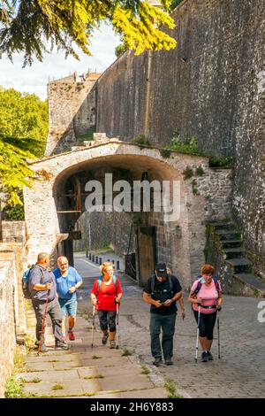 Pellegrini che camminano attraverso le porte della città a Camino de Santiago la via del pellegrinaggio di San Giacomo attraverso la città spagnola di Pamplona Navarra Spagna Foto Stock