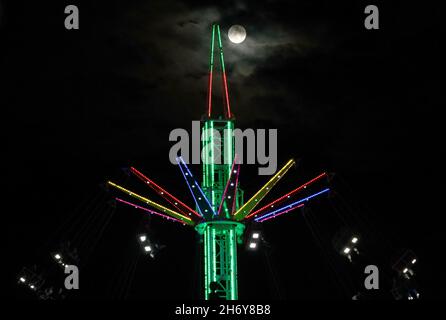 Leicester, Leicestershire, Regno Unito. 18 novembre 2021. La luna sorge dietro un giro nella zona fieristica durante le luci di Natale con l'evento ON. Credit Darren Staples/Alamy Live News. Foto Stock