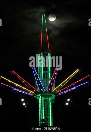 Leicester, Leicestershire, Regno Unito. 18 novembre 2021. La luna sorge dietro un giro nella zona fieristica durante le luci di Natale con l'evento ON. Credit Darren Staples/Alamy Live News. Foto Stock