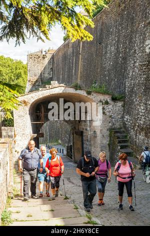 Pellegrini che camminano attraverso le porte della città a Camino de Santiago la via del pellegrinaggio di San Giacomo attraverso la città spagnola di Pamplona Navarra Spagna Foto Stock