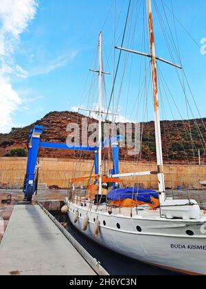 Bodrum, Turchia - 10.12.2021: Gru di riparazione yacht al molo. Marina di Kairos. Lo yacht in acqua è pronto per il sollevamento. Foto Stock