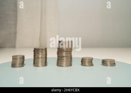 Coins pile sopra la tabella che presenta i piani finanziari. Piani ipotecari per la casa e l'ufficio utilizzando i soldi. Foto Stock