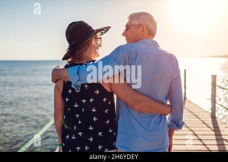 Coppia di famiglie anziane che camminano sul molo vicino al Mar Rosso. Le persone in pensione godendo la vacanza in Egitto tropicale godendo il paesaggio. Vista posteriore Foto Stock