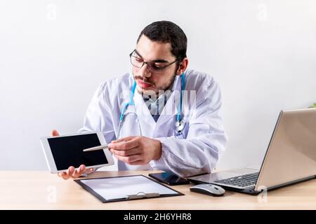 Bianco medico caucasico che lavora con una compressa nella sua clinica Foto Stock