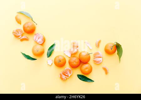 Clementine fresche con foglie su sfondo giallo, vista dall'alto Foto Stock