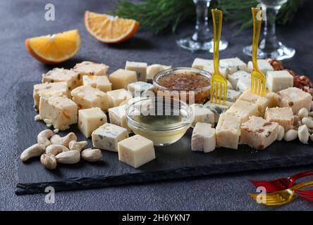 Assortimento di formaggi d'elite su una tavola d'ardesia su sfondo scuro. Spuntini per una festa del vino. Foto Stock