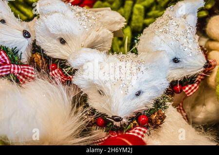 Ornamenti natalizi di volpe bianca con gioielli sulla testa con archi rossi e bacche di gingham - fuoco selettivo Foto Stock