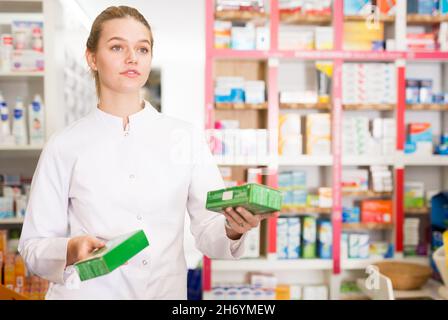 Giovane donna farmacista suggerendo compresse utili in farmacia Foto Stock