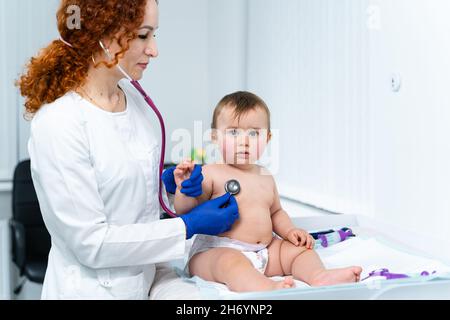 Pediatra che fornisce assistenza sanitaria per il suo bambino paziente nell'ufficio di una clinica specializzata per i bambini. Neonatologo. Appuntamento medico poco Foto Stock