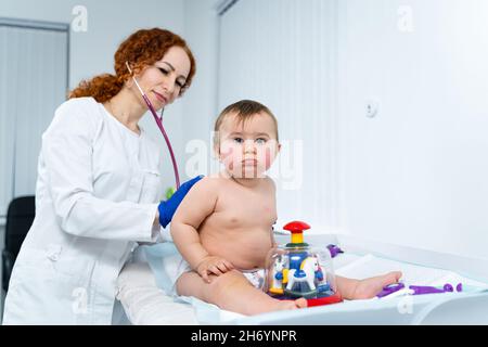 Pediatra che fornisce assistenza sanitaria per il suo bambino paziente nell'ufficio di una clinica specializzata per i bambini. Neonatologo. Appuntamento medico poco Foto Stock