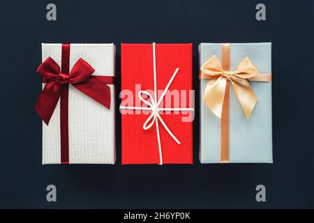 Tre confezioni regalo su sfondo nero. Concetto di Natale. Vista dall'alto, disposizione piatta, spazio di copia. Foto Stock