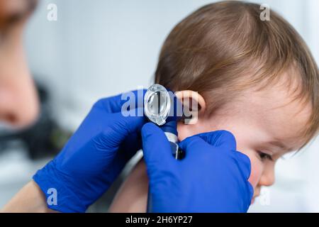 Il medico femminile dai capelli rossi esamina il bambino piccolo per meno di un anno in una clinica moderna. Pediatra durante l'esame del bambino in ospedale Foto Stock