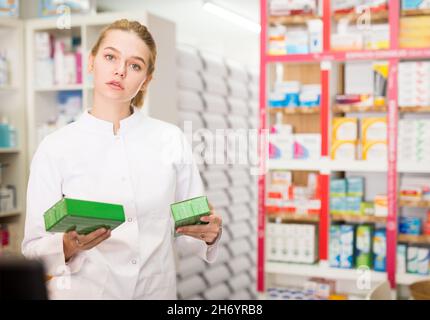 Giovane donna farmacista suggerendo compresse utili in farmacia Foto Stock
