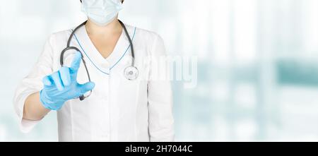 La mano del medico nei guanti blu preme il tasto virtuale nella priorità bassa dell'ospedale, concetto di tecnologia di innovazione medica Foto Stock