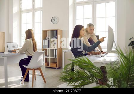 Persone aziendali che utilizzano i computer mentre lavorano insieme in un ambiente di lavoro moderno Foto Stock