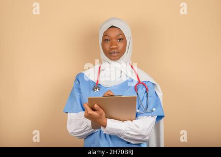 Giovane uomo di religione musulmana che tiene appunti e scrive qualcosa da vicino. Assistenza medica, assicurazione, prescrizione medica. Foto Stock