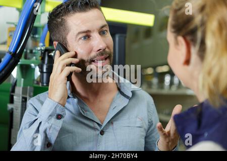 lavoratori di fabbrica che si occupano al telefono con il cliente Foto Stock