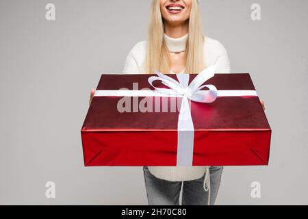 Sorridente giovane donna che tiene presente in studio Foto Stock
