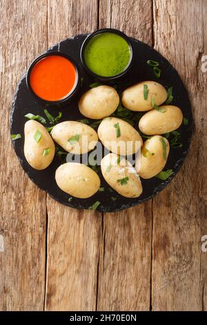 Le patate rugose Papas arrugadas sono un tradizionale piatto di patate bollite servito con un rojo mojo e salse mojo verde da vicino nel piatto sul tavolo. Foto Stock