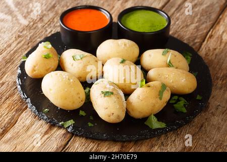 Patate rugose con salsa rossa e verde da vicino nel piatto sul tavolo. Orizzontale Foto Stock