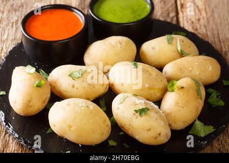 Le patate ruplice del cibo delle Canarie vengono bollite patate non pelate servite con due salse locali in primo piano su un piatto di ardesia sul tavolo. Orizzontale Foto Stock