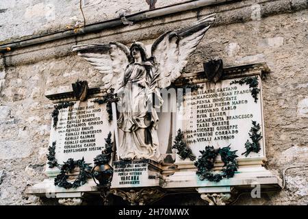 Pannello commemorativo con una scultura di un angelo nel cimitero di Varenna, Italia Foto Stock