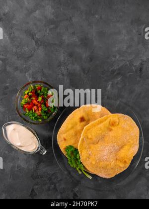 Pane piatto di mais fatto in casa cilantro verde salsa di pomodoro. Tortilla messicana Taco Quesadilla vegetale fatta a mano. Tradizionale indiano Makki ki roti pane top Foto Stock