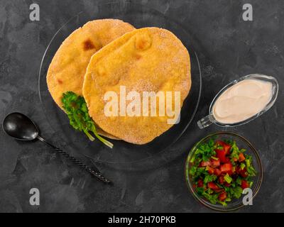 Pane piatto di mais fatto in casa cilantro verde salsa di pomodoro. Tortilla messicana Taco Quesadilla vegetale fatta a mano. Tradizionale indiano Makki ki roti pane top Foto Stock