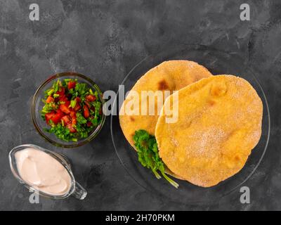 Pane piatto di mais fatto in casa cilantro verde salsa di pomodoro. Tortilla messicana Taco Quesadilla vegetale fatta a mano. Tradizionale indiano Makki ki roti pane top Foto Stock