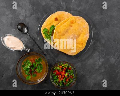 Pane piatto di mais fatto in casa cilantro verde salsa di pomodoro. Tortilla messicana Taco Quesadilla vegetale fatta a mano. Tradizionale indiano Makki ki roti pane top Foto Stock