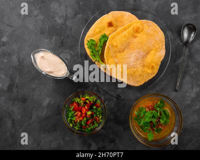 Pane piatto di mais fatto in casa cilantro verde salsa di pomodoro. Tortilla messicana Taco Quesadilla vegetale fatta a mano. Tradizionale indiano Makki ki roti pane top Foto Stock