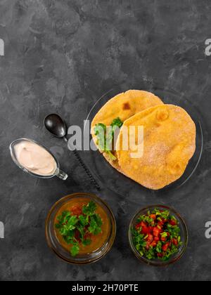 Pane piatto di mais fatto in casa cilantro verde salsa di pomodoro. Tortilla messicana Taco Quesadilla vegetale fatta a mano. Tradizionale indiano Makki ki roti pane top Foto Stock