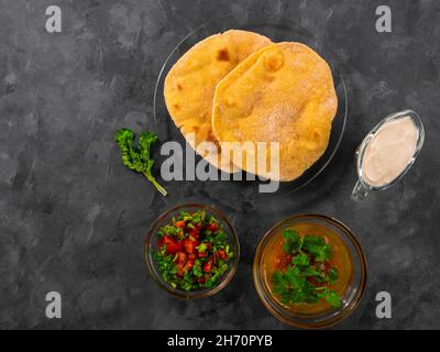 Pane piatto di mais fatto in casa cilantro verde salsa di pomodoro. Tortilla messicana Taco Quesadilla vegetale fatta a mano. Tradizionale indiano Makki ki roti pane top Foto Stock