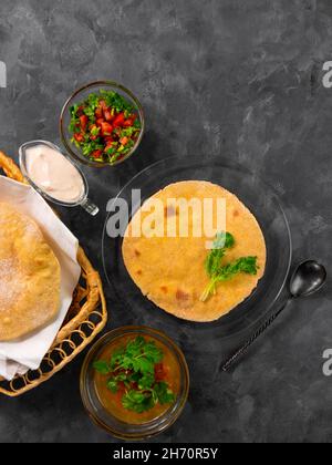 Pane piatto di mais fatto in casa cilantro verde salsa di pomodoro. Tortilla messicana Taco Quesadilla vegetale fatta a mano. Tradizionale indiano Makki ki roti pane top Foto Stock