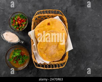 Pane piatto di mais fatto in casa cilantro verde salsa di pomodoro. Tortilla messicana Taco Quesadilla vegetale fatta a mano. Tradizionale indiano Makki ki roti pane top Foto Stock