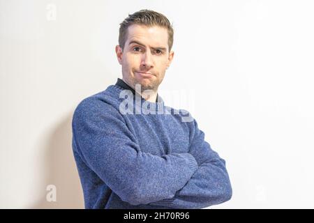 Primo piano dell'uomo in un maglione blu isolato su sfondo bianco. Foto Stock