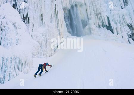 Femmina scalatore di ghiaccio ascendente collina nevosa Foto Stock