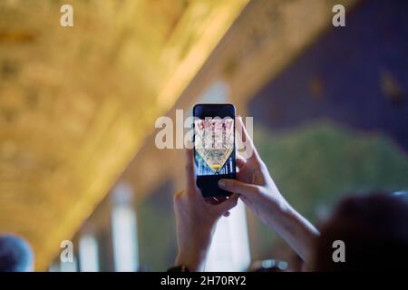 Persona che scatta foto con il telefono cellulare all'interno della chiesa Foto Stock