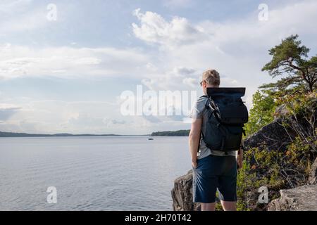 Uomo in piedi in mare e guardando la vista Foto Stock