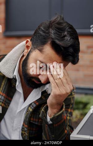 Giovane uomo che tocca la fronte Foto Stock