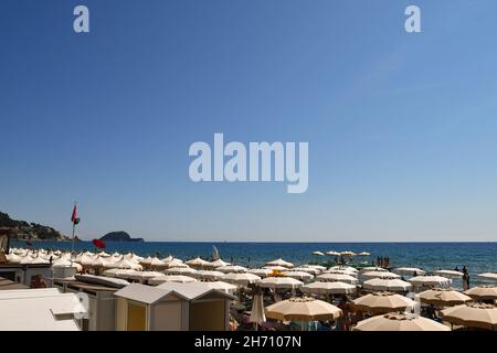 Vista rialzata della spiaggia con ombrelloni e dell'Isola della Gallinara sull'orizzonte marino in estate, Alassio, Savona, Liguria, Italia Foto Stock