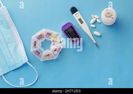 Maschere chirurgiche, termometro e termometro su blu Foto Stock