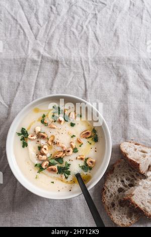 Ciotola di zuppa di sedano con prezzemolo tritato e nocciole, servita con pezzetti di pasta madre. Foto Stock