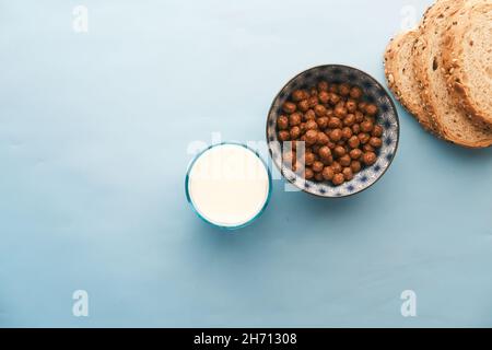 Vista dall'alto di fiocchi di mais al cioccolato, latte e pane su blu Foto Stock