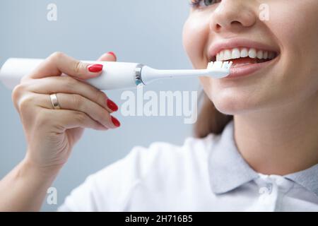 Primo piano ritagliato di un dentista femminile che mostra la corretta pulizia dei denti con lo spazzolino elettrico Foto Stock