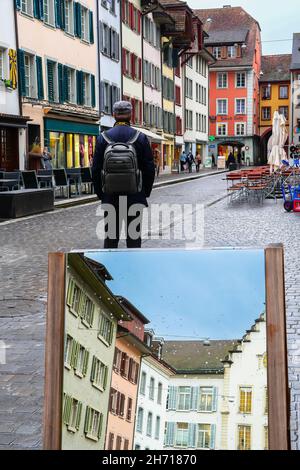 Aarau, Svizzera - 3 novembre 2021: Un uomo visita la città vecchia di Aarau, la capitale del cantone svizzero settentrionale di Argau. Un riflesso dello specchio stradale Foto Stock