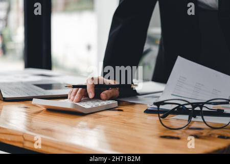 Primo piano contabile che lavora alla scrivania utilizzando la calcolatrice per calcolare il rapporto finanziario in ufficio. Donna d'affari che calcola il saldo di affari prepara le tasse Foto Stock