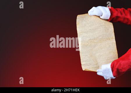 Babbo Natale tenendo un rotolo vuoto - Naughty e Nizza Lista su uno sfondo rosso. Mani e braccia solo con spazio di copia, . Foto Stock