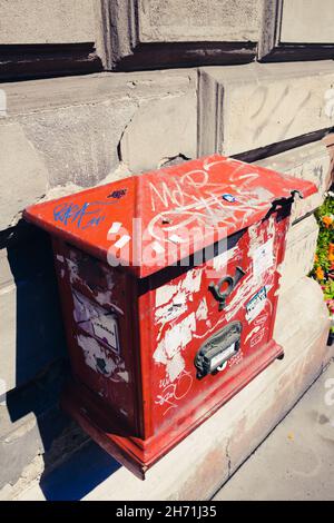 Vecchia cassetta postale da parete rossa coperta di adesivi in una strada di Budapest Ungheria Foto Stock